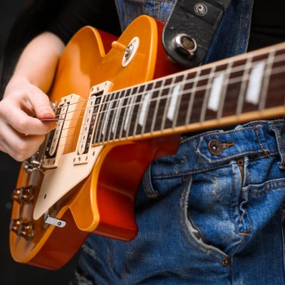 close up girl s hands guitar black background